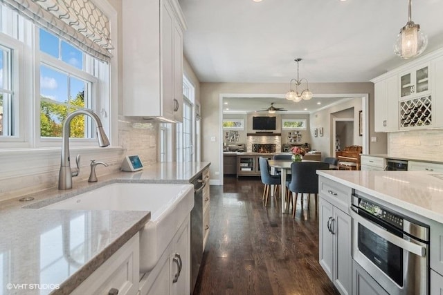 kitchen featuring pendant lighting, sink, light stone counters, and white cabinets