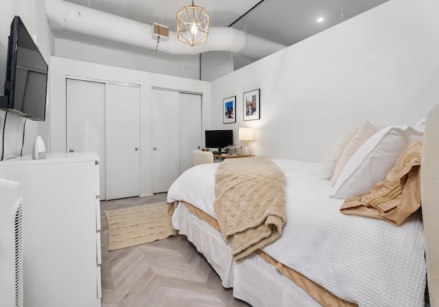 bedroom with multiple closets and light parquet floors