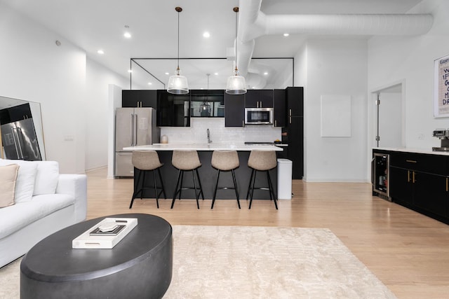 kitchen with a breakfast bar area, tasteful backsplash, a center island, appliances with stainless steel finishes, and pendant lighting