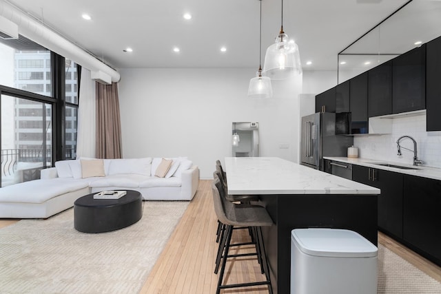 kitchen featuring sink, a kitchen breakfast bar, a center island, decorative backsplash, and decorative light fixtures