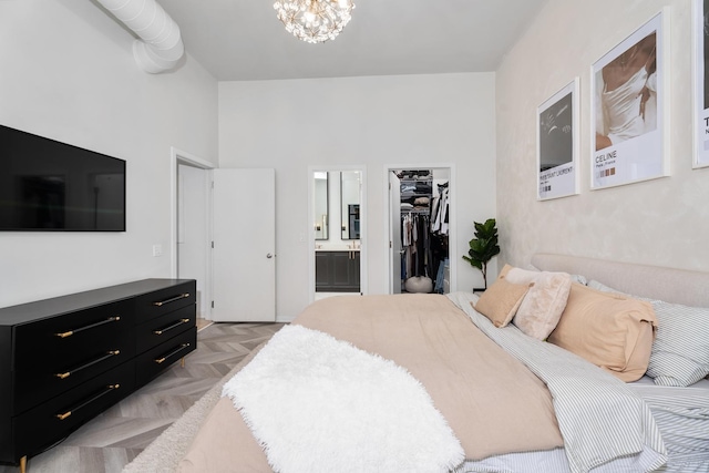 bedroom featuring light parquet floors, connected bathroom, a notable chandelier, a walk in closet, and a closet