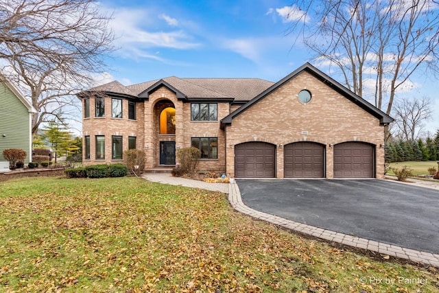 traditional-style house with a shingled roof, a front lawn, a garage, aphalt driveway, and brick siding