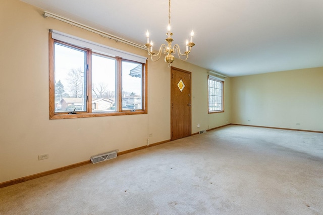 carpeted spare room featuring a notable chandelier