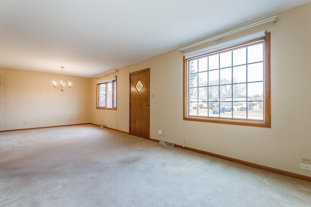 carpeted empty room featuring a notable chandelier