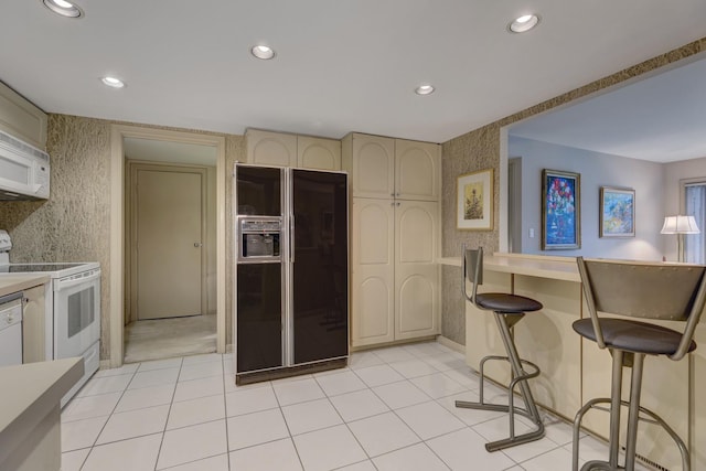 2 Oak Brook Club Dr Unit B209, Oak Brook, IL 60523 - kitchen with white appliances, recessed lighting, light tile patterned floors, cream cabinetry, and a kitchen bar