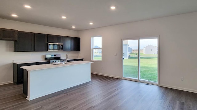 kitchen with an island with sink, appliances with stainless steel finishes, sink, and dark hardwood / wood-style flooring