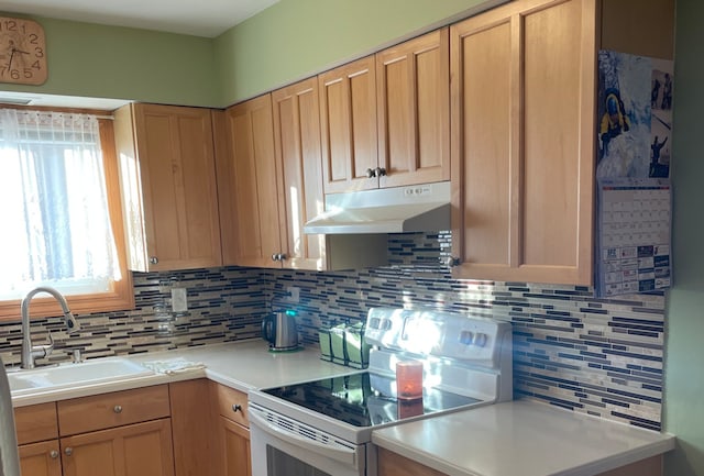 kitchen featuring tasteful backsplash, light brown cabinetry, sink, and electric range