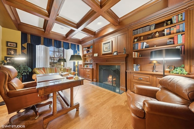 living area featuring beamed ceiling, light hardwood / wood-style flooring, coffered ceiling, a premium fireplace, and built in shelves