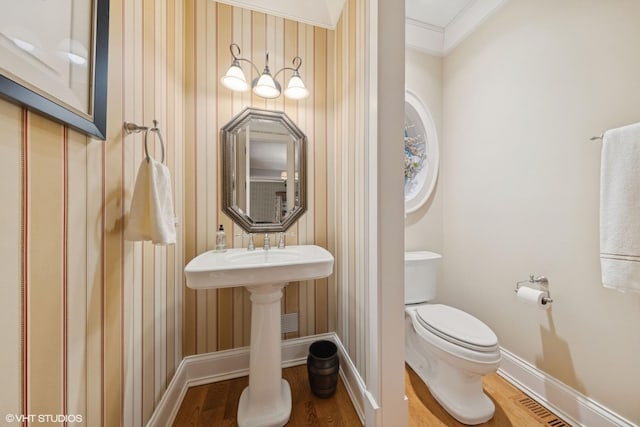 bathroom featuring crown molding, toilet, and hardwood / wood-style floors