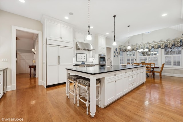 kitchen with pendant lighting, sink, white cabinets, and light wood-type flooring