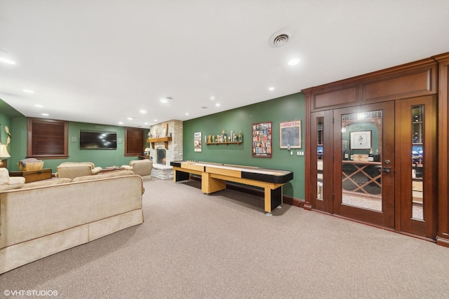 rec room with a fireplace and light colored carpet