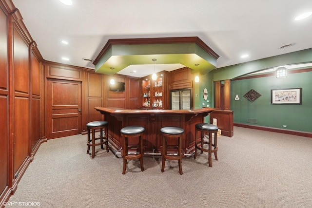 bar with light colored carpet, stainless steel built in refrigerator, and hanging light fixtures