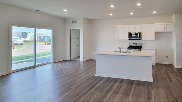 kitchen with appliances with stainless steel finishes, dark hardwood / wood-style floors, an island with sink, sink, and white cabinets