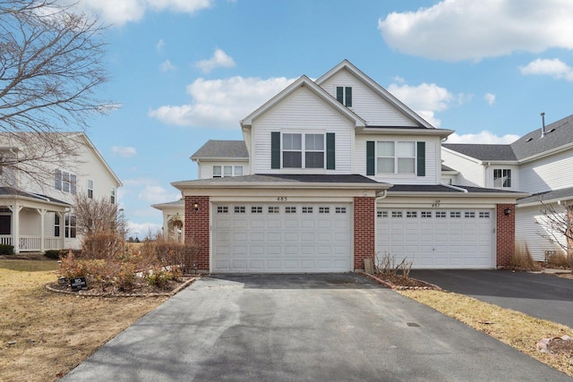 traditional-style house featuring aphalt driveway, brick siding, and an attached garage