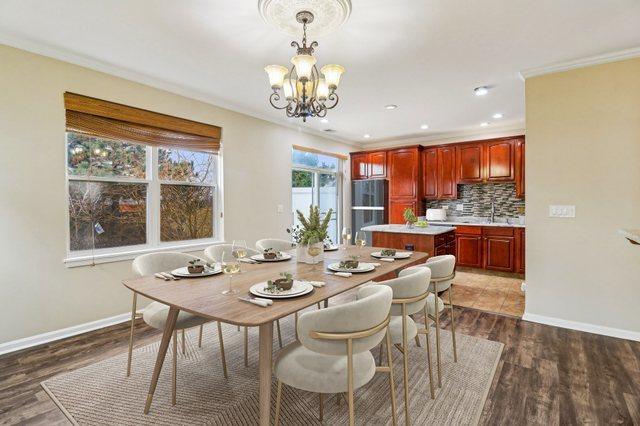 dining space featuring wood finished floors, baseboards, a chandelier, and ornamental molding