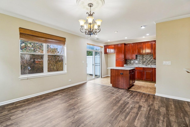 kitchen with wood finished floors, hanging light fixtures, light countertops, a notable chandelier, and tasteful backsplash