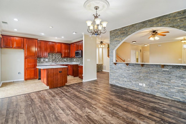 kitchen featuring stainless steel microwave, ceiling fan with notable chandelier, and arched walkways