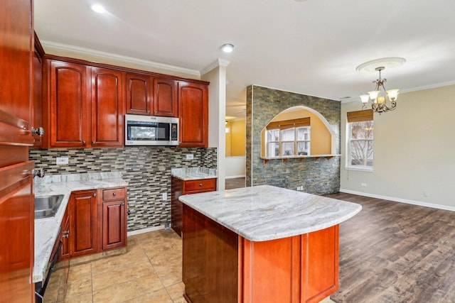 kitchen featuring dark brown cabinets, stainless steel microwave, backsplash, and ornamental molding