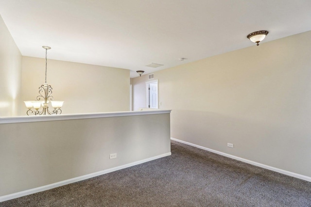 carpeted empty room featuring an inviting chandelier and baseboards