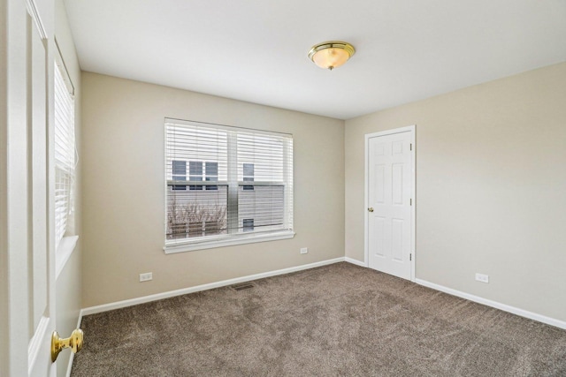 spare room with carpet, visible vents, and baseboards