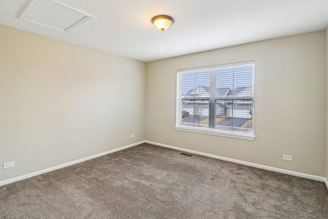 unfurnished room featuring visible vents, carpet flooring, attic access, and baseboards