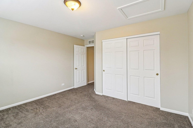 unfurnished bedroom with attic access, baseboards, visible vents, and carpet floors