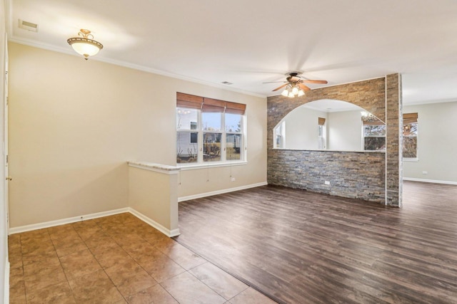 spare room featuring wood finished floors, baseboards, visible vents, ceiling fan, and crown molding