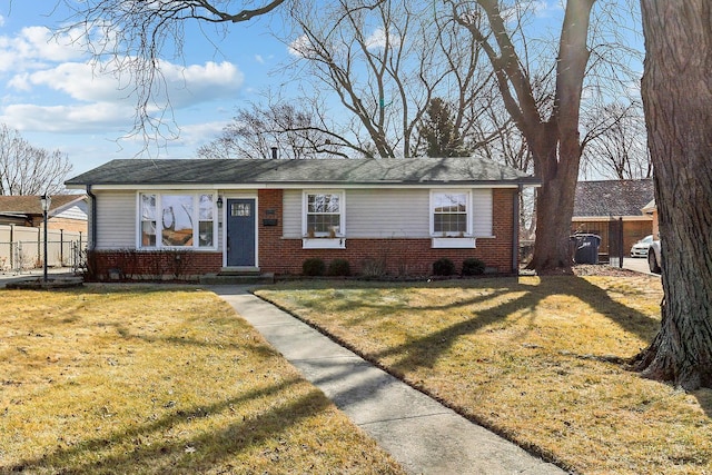 view of front of property with entry steps, brick siding, fence, and a front lawn