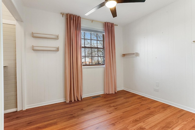 empty room with baseboards, a ceiling fan, visible vents, and light wood-style floors