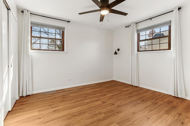 unfurnished room featuring light wood-type flooring, visible vents, baseboards, and a wealth of natural light