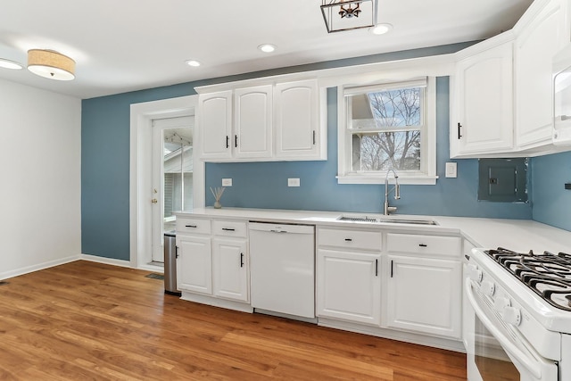 kitchen with white appliances, light countertops, light wood-type flooring, white cabinetry, and a sink