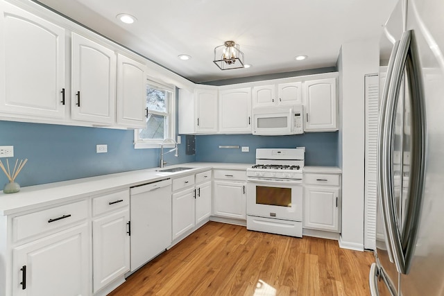 kitchen featuring white appliances, a sink, white cabinetry, light countertops, and light wood-type flooring