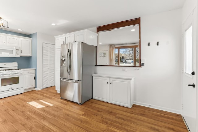 kitchen featuring white appliances, light wood-style flooring, white cabinets, and recessed lighting