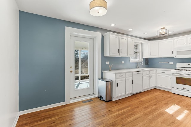 kitchen featuring light wood-style floors, white appliances, visible vents, and a sink