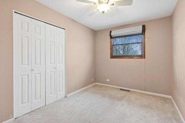 unfurnished bedroom with ceiling fan, light colored carpet, and a closet