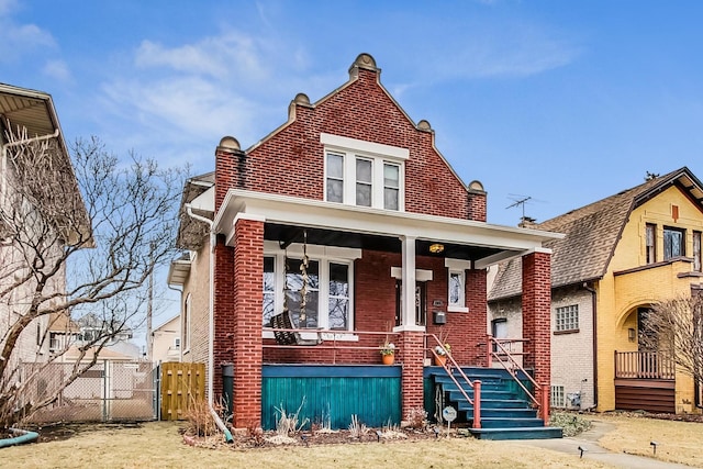 view of front of home featuring brick siding, a porch, and fence