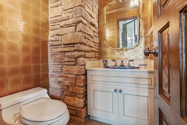 bathroom featuring vanity, tile walls, and toilet