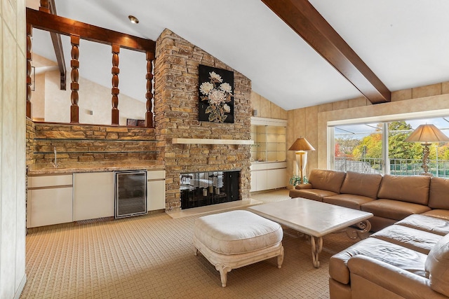 living room with wine cooler, beam ceiling, a stone fireplace, and high vaulted ceiling