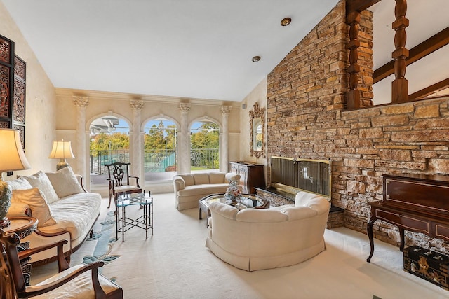 living room featuring a stone fireplace and high vaulted ceiling