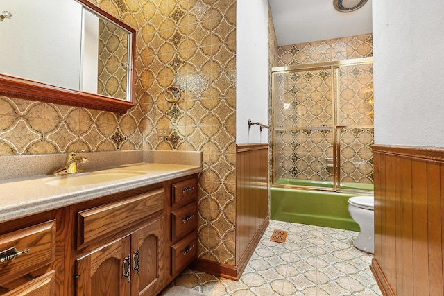 full bathroom featuring toilet, vanity, and shower / bath combination with glass door