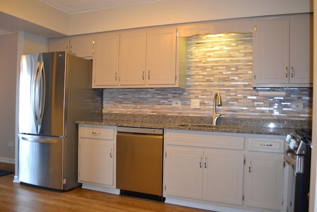 kitchen featuring white cabinetry, appliances with stainless steel finishes, sink, and dark stone counters