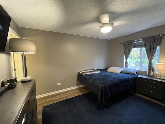 bedroom with ceiling fan, dark hardwood / wood-style floors, and a textured ceiling