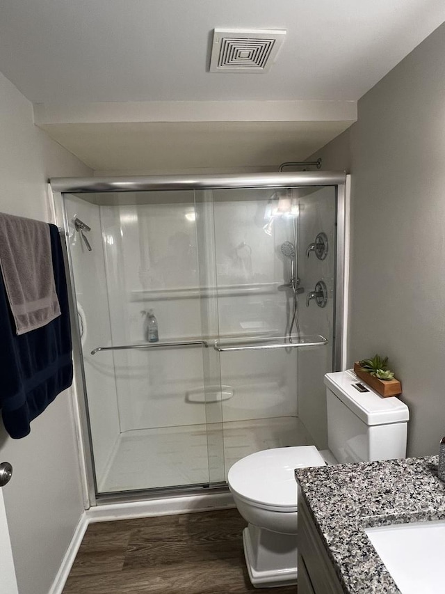 bathroom with walk in shower, vanity, toilet, and wood-type flooring