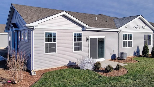 rear view of property featuring a yard and cooling unit