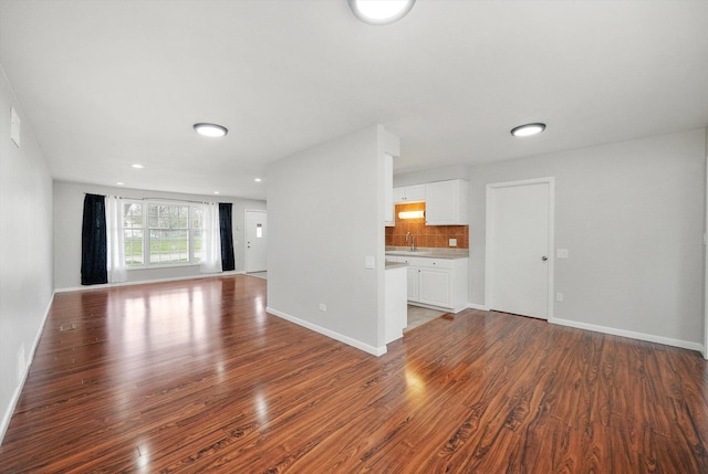 unfurnished living room featuring baseboards, a sink, and wood finished floors