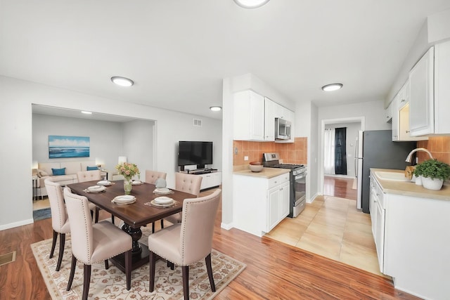 dining room featuring light wood-style flooring, baseboards, and visible vents