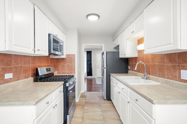 kitchen featuring light countertops, tasteful backsplash, appliances with stainless steel finishes, and a sink