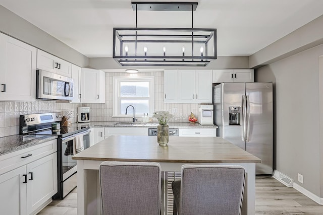 kitchen featuring stainless steel appliances, white cabinetry, and a kitchen island