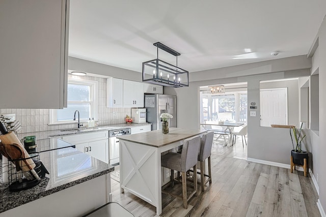 kitchen featuring sink, hanging light fixtures, white cabinets, stainless steel appliances, and backsplash