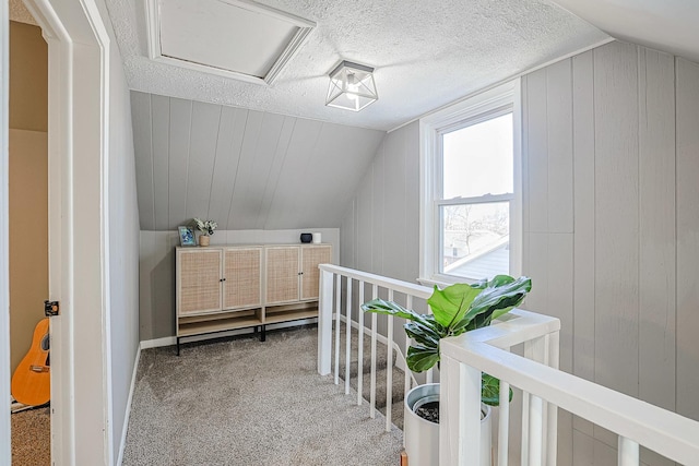 bonus room featuring vaulted ceiling, carpet, a textured ceiling, and wood walls